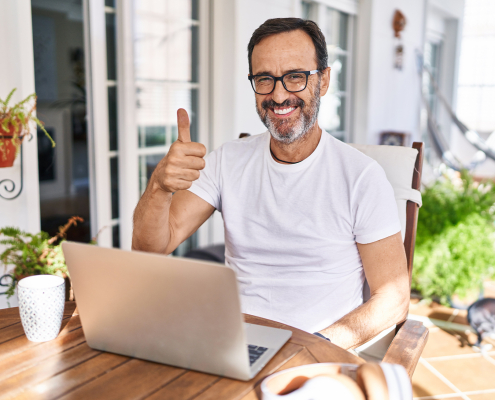 Mann sitzt am Laptop und zeigt einen Daumen hoch