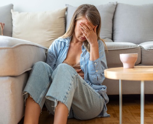 Junge Frau sitzt auf dem Boden im Wohnzimmer